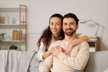 Mutlu bir eş evdeki kanepede kocasına sarılıyor.