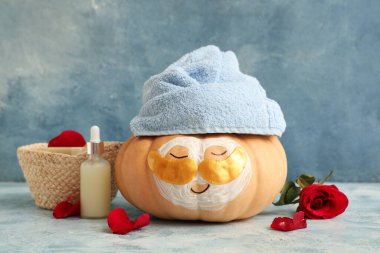 Göz altı bantları, havlu, serum ve gül çiçekli komik balkabağı.