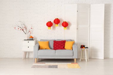 Çin Yeni Yılı için dekore edilmiş oturma odasının içi kanepe, masa ve katlanır ekran ile süslenmiş.