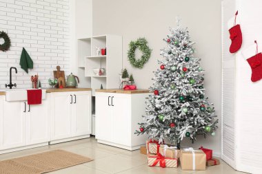 Mutfağın içinde tezgahlar, Noel ağacı ve hediyeler var.