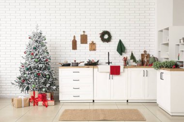 Mutfağın içinde tezgahlar, Noel ağacı ve hediyeler var.