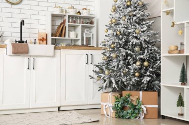 Mutfağın içinde tezgahlar, Noel ağacı ve hediyeler var.