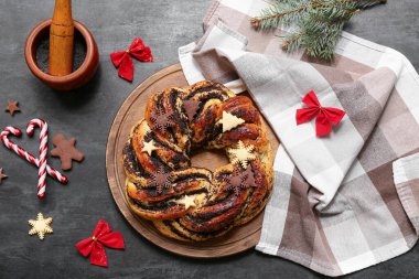 Lezzetli Noel pastası çelengi, peçete, süslemeler ve koyu arkaplanda haşhaş tohumlu kompozisyon