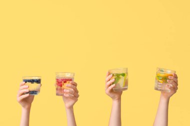 Sarı zemin üzerinde aşılanmış su olan birçok el