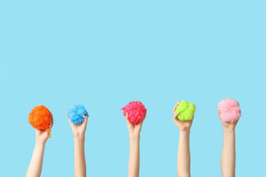 Mavi arka planda farklı banyo süngeri olan kadın elleri