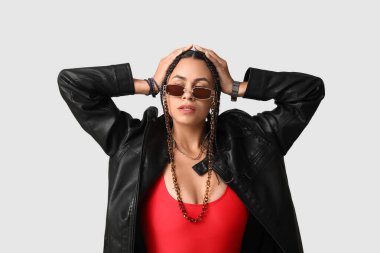 Gri arka planda rastaları olan şık, Afro-Amerikalı bir kadın.