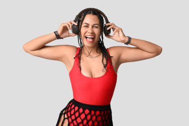 Gri arka planda rastalı kulaklıklı Afro-Amerikan bir kadın.