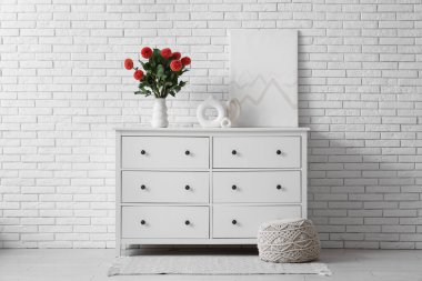 Evdeki çekmecelerin üzerinde portakal çiçekleri olan vazo.