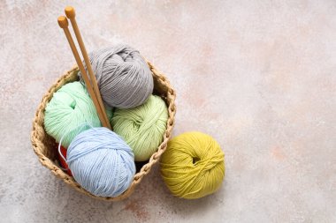 Renkli örgü ipliği ve hafif grunge arka planında iğneler olan hasır sepet.