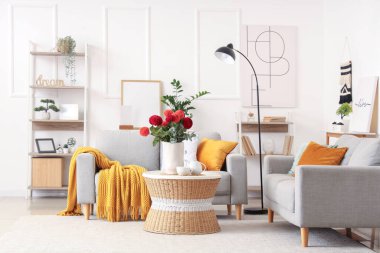 Gri koltukları olan şık bir oturma odası, güzel yıldız çiçekleri ve kahve masasında bir fincan çay.