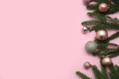 Pembe arka planda Noel topları ve köknar dallarıyla kompozisyon