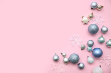 Noel topları ve pembe arka planda dekoratif kar taneleri olan güzel bir kompozisyon.