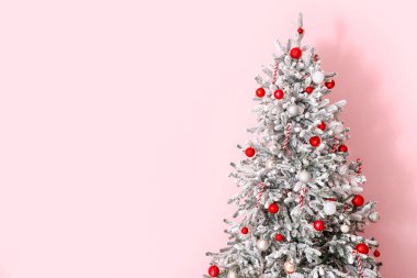 Odadaki pembe duvarın yanındaki süslü Noel ağacı.