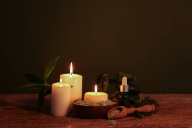 Koyu ahşap masa üzerinde yanan mumlar ve bambu saplı spa kompozisyonu