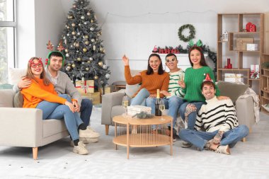 Evde yeni yılı kutlamak için şampanya içen bir grup genç.