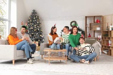 Evde yeni yılı kutlamak için şampanya içen bir grup genç.