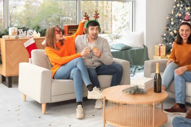 Evde yeni yılı kutlamak için şampanya içen genç bir çift.