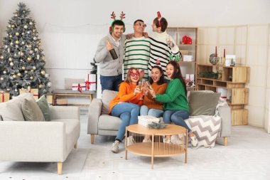 Evde yeni yılı kutlamak için şampanya içen bir grup genç.