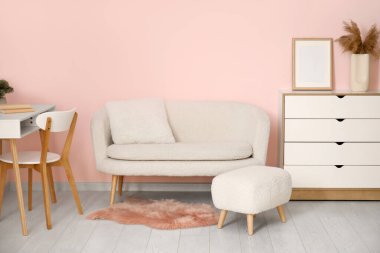 Beyaz kanepesi ve ayaklığı olan modern bir oturma odası.