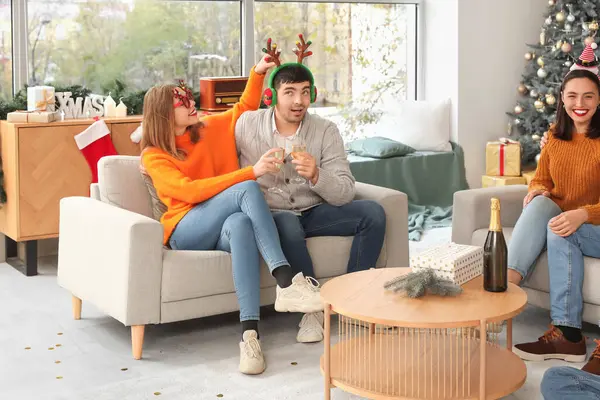 Evde yeni yılı kutlamak için şampanya içen genç bir çift.