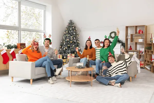 Evde yeni yılı kutlamak için şampanya içen bir grup genç.