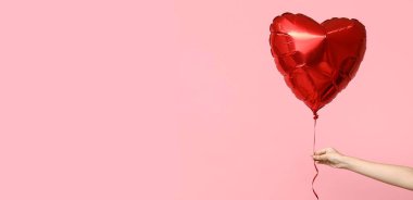 Pembe arka planda el ele tutuşan kalp şeklinde balon ve mesaj için yer. Sevgililer Günü kutlaması