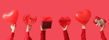 Birçok el, kırmızı arka planda kalp şeklinde balonlar ve hediyeler tutuyor. Sevgililer Günü kutlaması