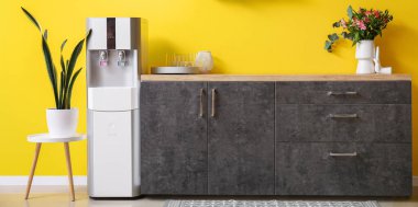 Sarı duvarın yanında modern su soğutuculu mutfağın içi.