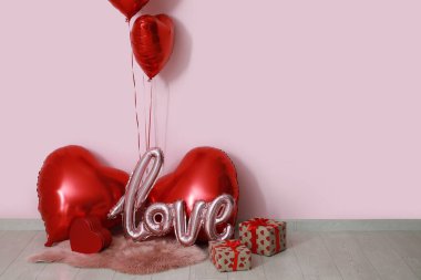 Kalp şeklinde balonlar ve leylak duvarın yanında hediye kutuları. Sevgililer Günü kutlaması