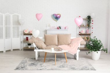 Sevgililer Günü kutlamaları için rahat kanepesi ve süslemeleri olan modern oturma odasının içinde.