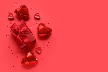 Kalp şeklinde balonları ve kırmızı arka planda mumları olan bir hediye kutusu. Sevgililer Günü kutlaması