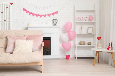 Beyaz kanepeli, şömineli ve Sevgililer Günü kutlaması için dekorlu festival salonu.