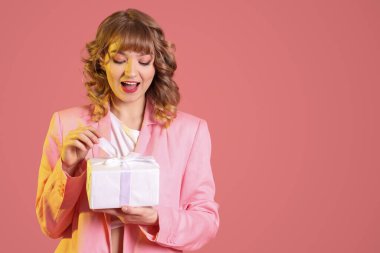 Pembe arka planda hediye kutusu olan güzel bir genç kadın. Sevgililer Günü kutlaması