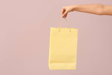 Işık arka planında kağıt alışveriş torbası olan bir kadın. Sevgililer Günü kutlaması