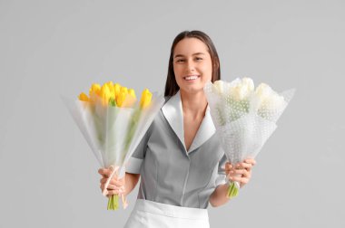 Hafif arka planda lale buketleri olan genç oda hizmetçisi. Uluslararası Kadınlar Günü