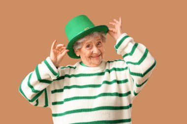 Bej arka planda Aziz Patrick Günü kutlamaları için cüce şapkalı mutlu yaşlı kadın.
