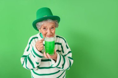 Leprikon şapkalı yaşlı kadın. Yanında bir kupa yeşil bira. St. Patrick Günü kutlamaları için.