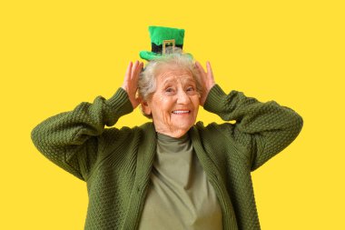 Sarı arka planda cüce şapkalı mutlu son sınıf kadını. Aziz Patrick Günü kutlaması