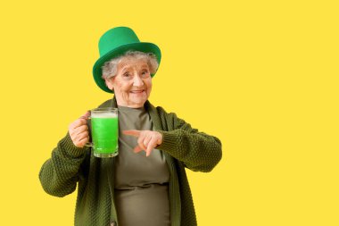 Sarı arka planda yeşil bira kupasını gösteren cüce şapkalı mutlu son sınıf kadını. Aziz Patrick Günü kutlaması