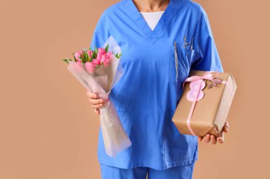 Laleleri ve kahverengi arka planda hediyeleri olan olgun bir dişçi. Yakın plan. Uluslararası Kadınlar Günü kutlamaları