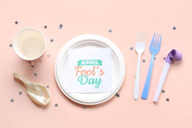 Bej arkaplanda 1 Nisan için şenlikli kartpostal ve parti dekoruna sahip masa ayarları