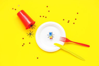 Sarı arkaplanda 1 Nisan şakaları için sahte örümcekler, palyaço çizmeleri ve konfeti.