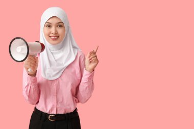 Pembe arka plandaki bir şeyi işaret eden megafonlu genç Asyalı Müslüman kadın. Ulusal Duyulma Günü