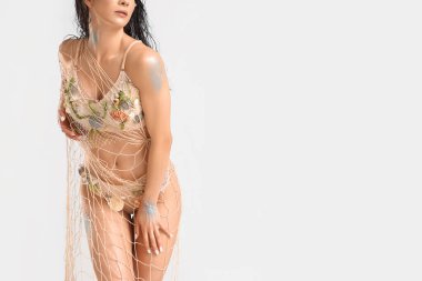 Gri arkaplanlı, efsanevi deniz kızı gibi giyinmiş güzel bir kadın.