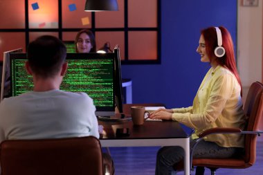 Genç bayan programcı geceleri ofiste bilgisayarla çalışıyor.