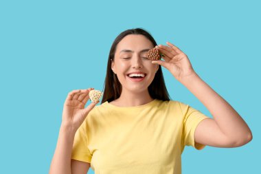 Çikolata kaplı, mavi arka planda çilekleri olan güzel genç bir kadın.