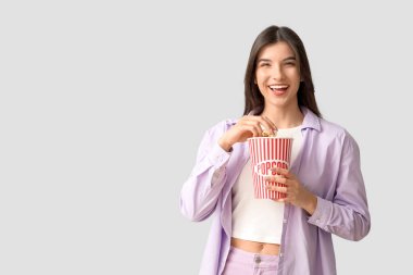 Beyaz arka planda patlamış mısır yiyen genç ve güzel bir kadın.