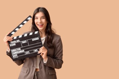 Bej arka planda film alkışları olan genç ve güzel bir kadın.