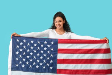 Mavi arka planda Amerikan bayrağı olan güzel, mutlu, Afro-Amerikan bir kadın.