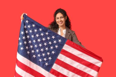 Kırmızı arka planda Amerikan bayrağı olan güzel, mutlu, Afro-Amerikalı bir iş kadını.